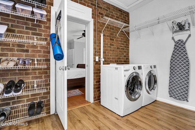 clothes washing area with ceiling fan, ornamental molding, light hardwood / wood-style floors, and brick wall