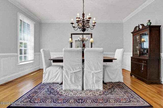 dining space with crown molding, a notable chandelier, and light hardwood / wood-style floors