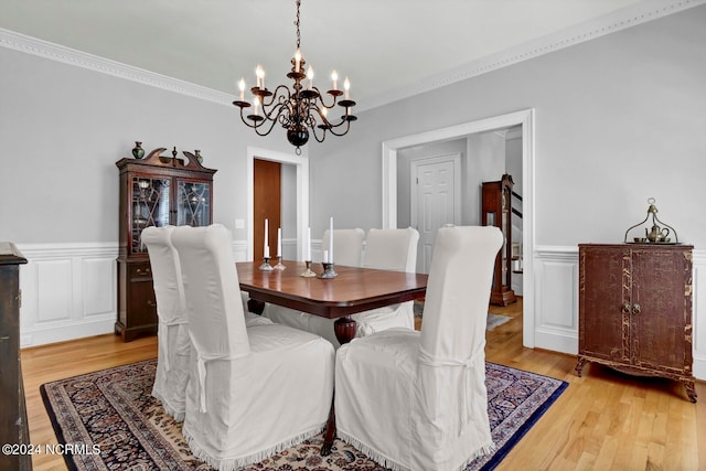 dining room with light hardwood / wood-style flooring, ornamental molding, and a notable chandelier