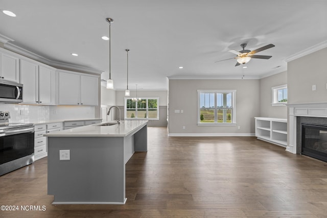 kitchen with white cabinets, stainless steel appliances, sink, hanging light fixtures, and ornamental molding