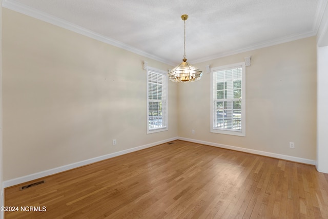 unfurnished room with a wealth of natural light, a chandelier, ornamental molding, and light wood-type flooring