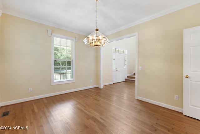 unfurnished dining area with hardwood / wood-style floors, crown molding, and a chandelier