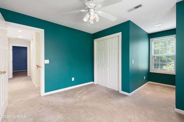 unfurnished bedroom featuring ceiling fan, a closet, a textured ceiling, and carpet floors