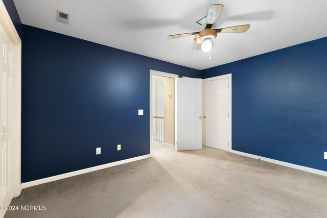 unfurnished bedroom with ceiling fan, a textured ceiling, and carpet flooring