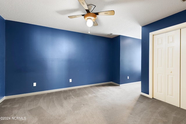 unfurnished bedroom with ceiling fan, a closet, a textured ceiling, and carpet floors