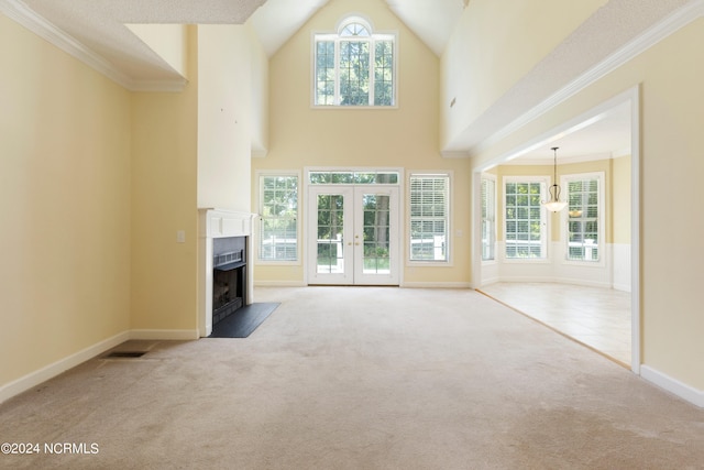 unfurnished living room with light carpet, high vaulted ceiling, a healthy amount of sunlight, and french doors