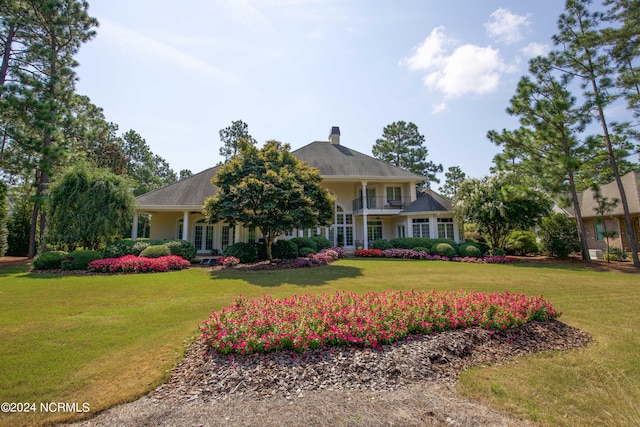 view of front of home featuring a front yard and a balcony