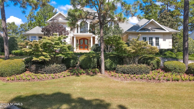 view of front of property with a balcony, stucco siding, a front yard, and french doors