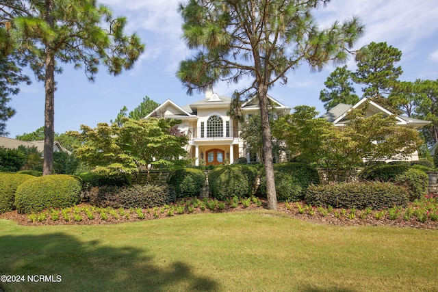 view of front of property featuring a balcony, a front lawn, and stucco siding