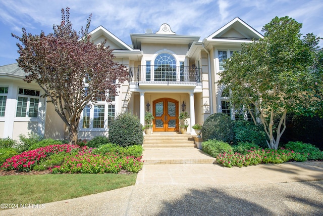 view of front of house featuring french doors, a balcony, and stucco siding