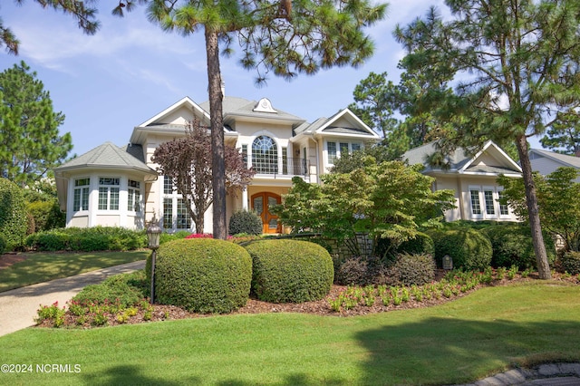 view of front of property featuring french doors, a front lawn, a balcony, and stucco siding