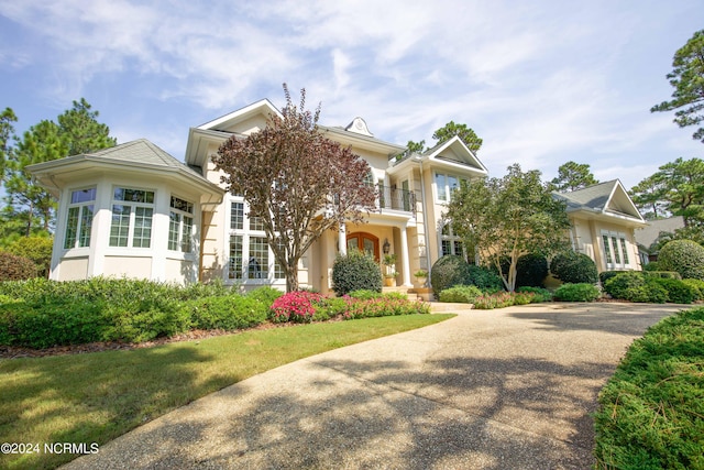 view of front of house featuring a balcony, driveway, and stucco siding