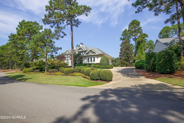 view of front of property featuring a chimney, concrete driveway, and a front yard