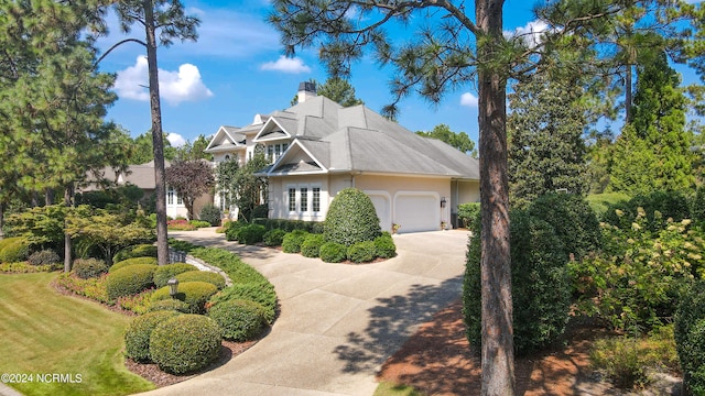 view of front of property with a garage, concrete driveway, a chimney, and stucco siding