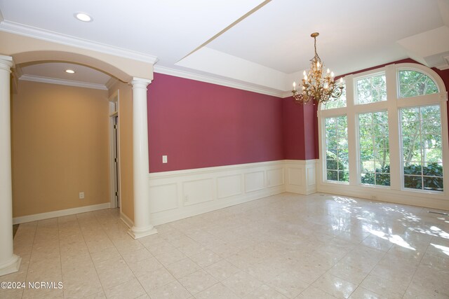 spare room with a wealth of natural light, a wainscoted wall, decorative columns, and recessed lighting