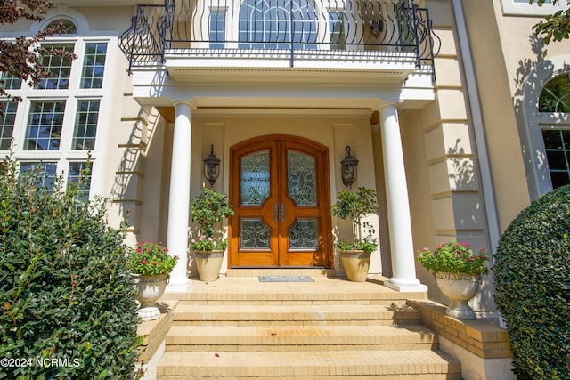 doorway to property featuring a balcony, stucco siding, and french doors