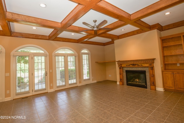 unfurnished living room featuring coffered ceiling, a glass covered fireplace, beam ceiling, and a healthy amount of sunlight