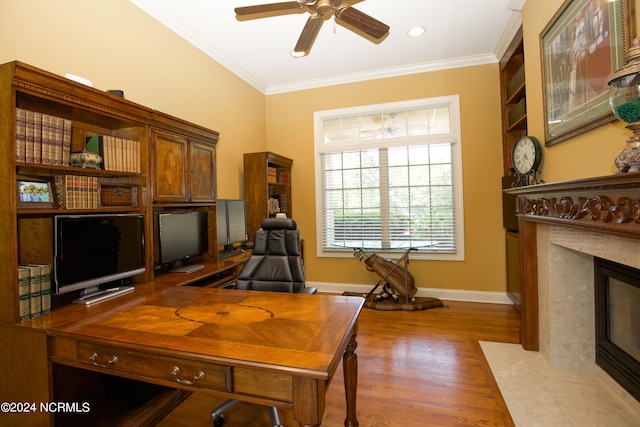 office space featuring ceiling fan, a fireplace, wood finished floors, baseboards, and crown molding