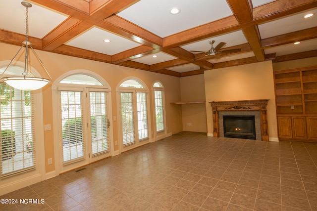 unfurnished living room with beam ceiling, visible vents, a ceiling fan, a glass covered fireplace, and coffered ceiling