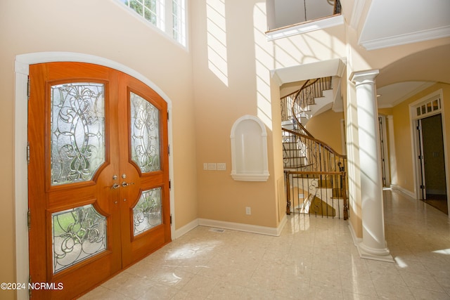 entryway with ornamental molding, french doors, decorative columns, and a towering ceiling