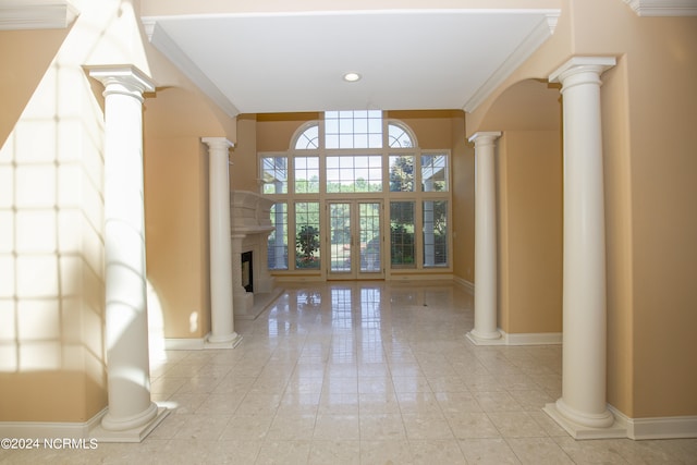 foyer with decorative columns, baseboards, a fireplace with raised hearth, and crown molding