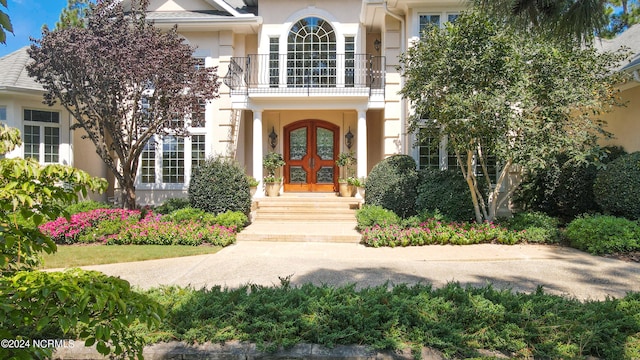 property entrance with french doors, a balcony, and stucco siding