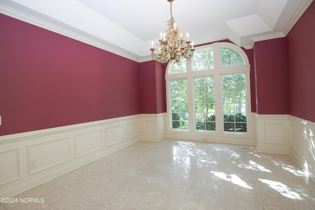 unfurnished room featuring an inviting chandelier, a decorative wall, a wealth of natural light, and wainscoting