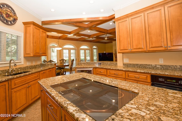 kitchen featuring coffered ceiling, brown cabinetry, light stone counters, black electric cooktop, and a sink