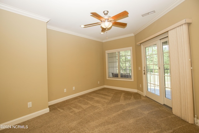 carpeted spare room featuring baseboards, ceiling fan, visible vents, and crown molding