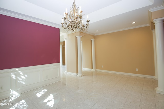 spare room featuring ornate columns, ornamental molding, and a decorative wall