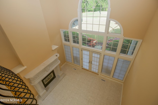 living room with light floors, a high ceiling, a glass covered fireplace, and baseboards