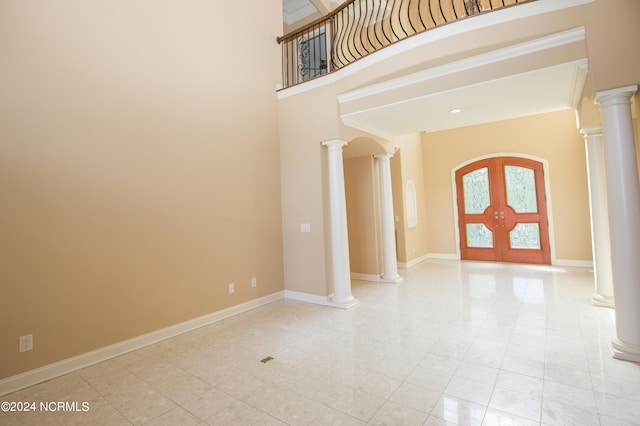 entrance foyer featuring decorative columns, a high ceiling, baseboards, and french doors