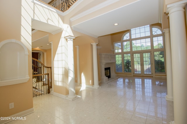 tiled living room featuring baseboards, a high ceiling, a premium fireplace, and ornate columns