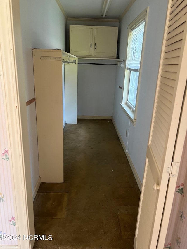 hallway featuring concrete flooring and baseboards