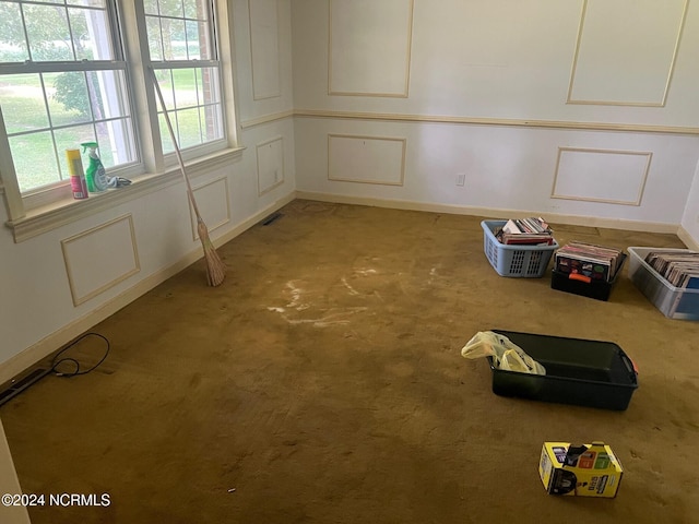 carpeted empty room featuring visible vents and a decorative wall