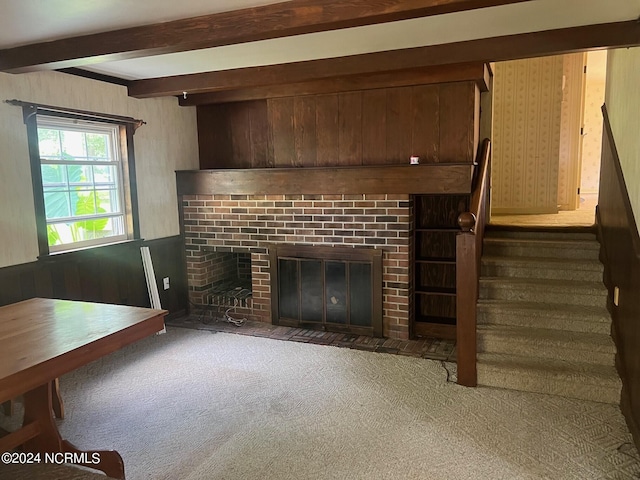 unfurnished living room with beam ceiling, dark carpet, and a brick fireplace