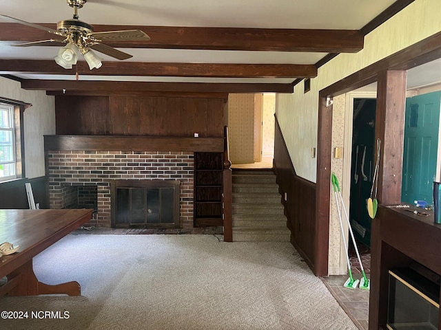 living room with a brick fireplace, wood walls, stairway, and beam ceiling