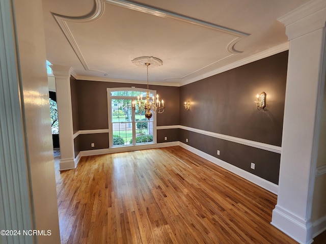 unfurnished room with baseboards, wood finished floors, an inviting chandelier, and ornamental molding