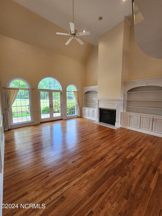 unfurnished living room featuring a fireplace with flush hearth, built in features, wood finished floors, high vaulted ceiling, and a ceiling fan