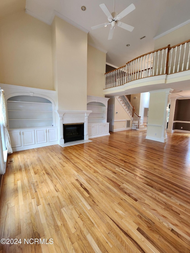 unfurnished living room featuring a fireplace with flush hearth, wood finished floors, a ceiling fan, and ornamental molding