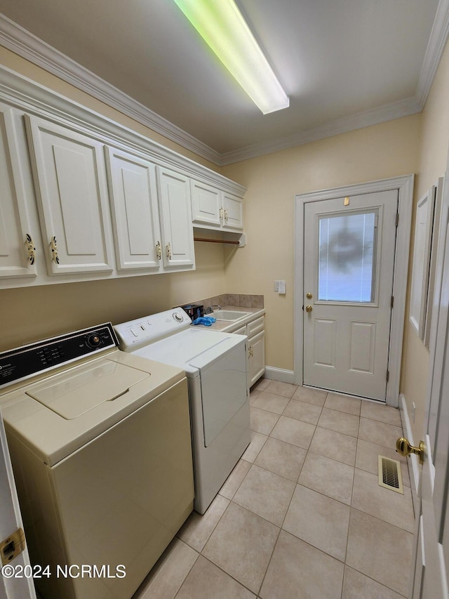 laundry area featuring baseboards, washing machine and clothes dryer, light tile patterned flooring, cabinet space, and crown molding