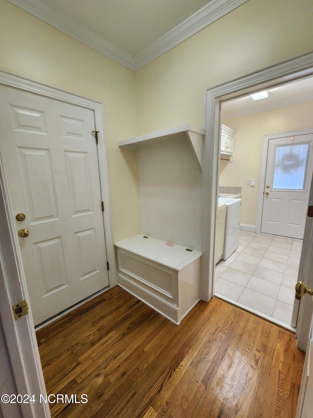 mudroom with light wood finished floors, ornamental molding, and separate washer and dryer