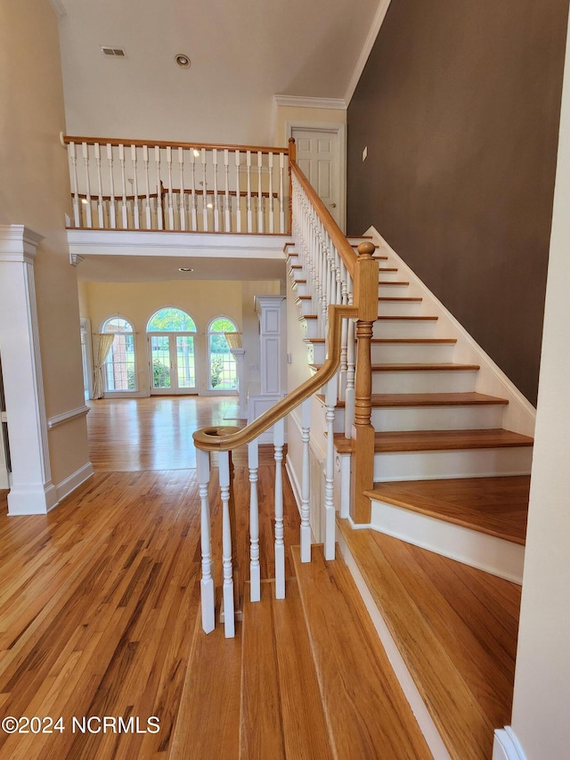 staircase featuring visible vents, baseboards, a towering ceiling, and wood finished floors