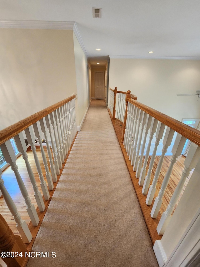 hallway featuring baseboards, visible vents, recessed lighting, ornamental molding, and light carpet