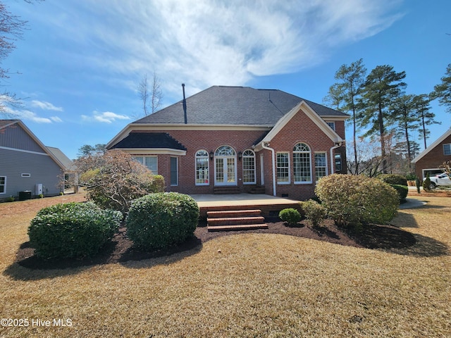 rear view of property featuring brick siding, a lawn, and french doors