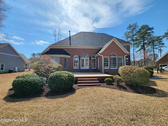 rear view of house featuring french doors, brick siding, and a lawn