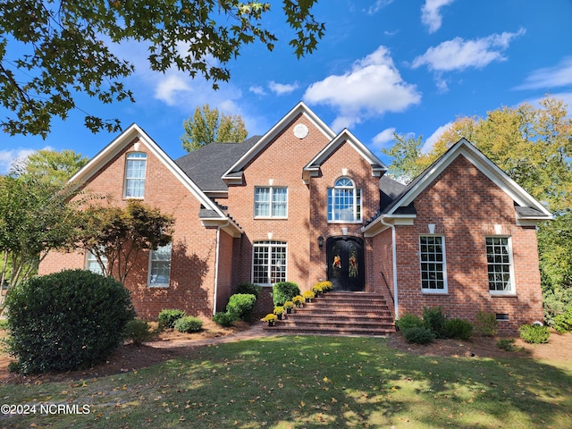 rear view of house with a shingled roof, a lawn, french doors, and brick siding