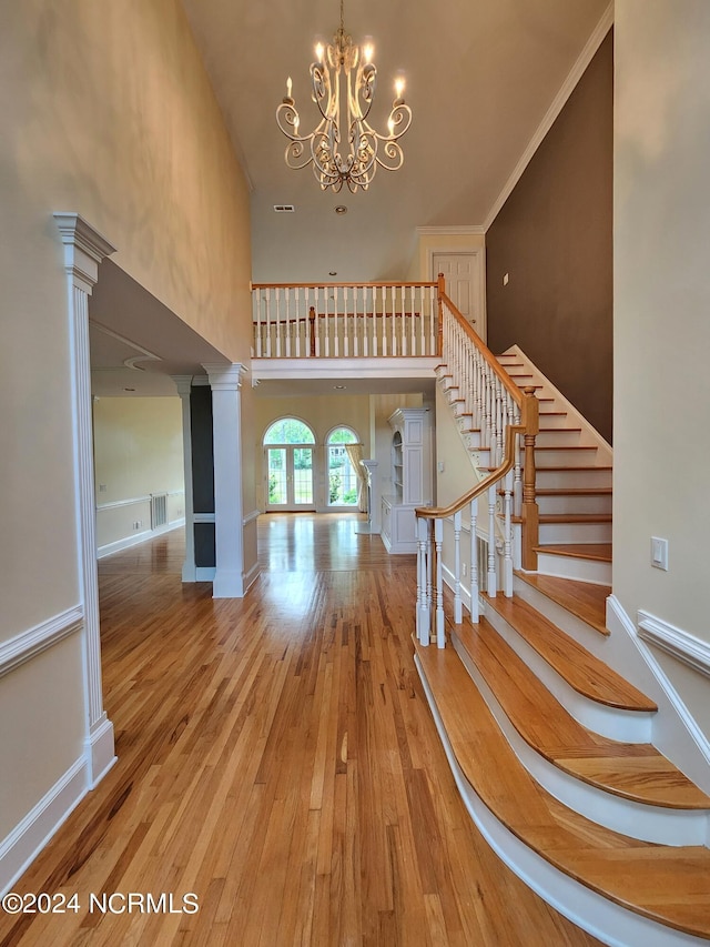 entrance foyer with visible vents, a chandelier, stairway, a high ceiling, and hardwood / wood-style flooring