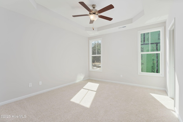 unfurnished room with light carpet, a tray ceiling, and ceiling fan