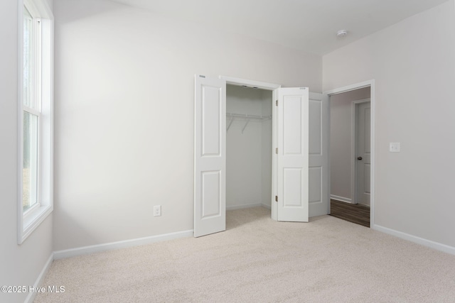 unfurnished bedroom with light colored carpet and a closet